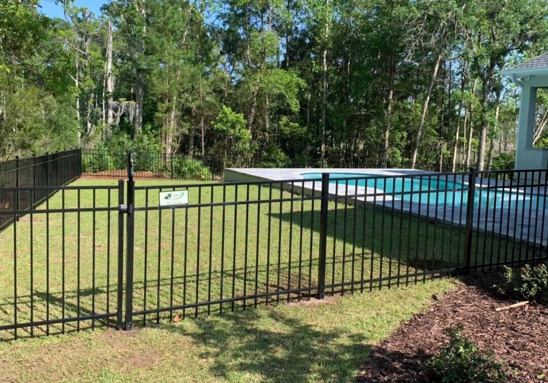 A pool and fence in the middle of a yard.